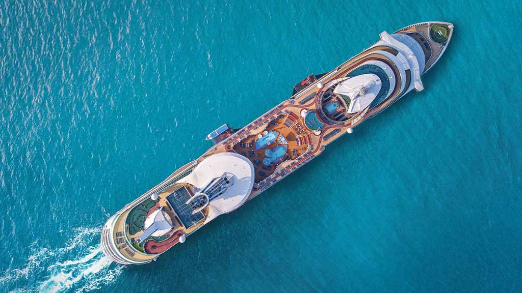 Aerial view of a modern cruise ship sailing through bright blue water