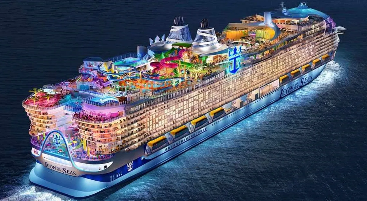 Icon of the Seas sailing at night with its upper-deck attractions lit